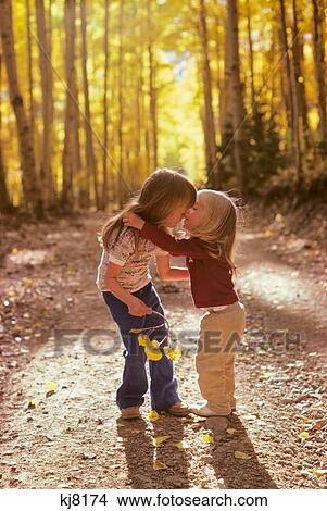 Picture - 1970s TWO LITTLE GIRLS SISTERS WALKING HUGGING IN AUTUMN WOODS ON NATURE TRAIL. Fotosearch