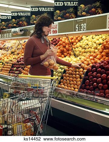1970s WOMAN GROCERY STORE SHOPPING CART SELECTING ORANGES IN PRODUCE DEPARTMENT OF FOOD SUPERMARKET View Large Photo Image Stock Image - 1970s WOMAN GROCERY STORE SHOPPING CART SELECTING ORANGES IN PRODUCE DEPARTMENT OF FOOD SUPERMARKET. Fotosearch