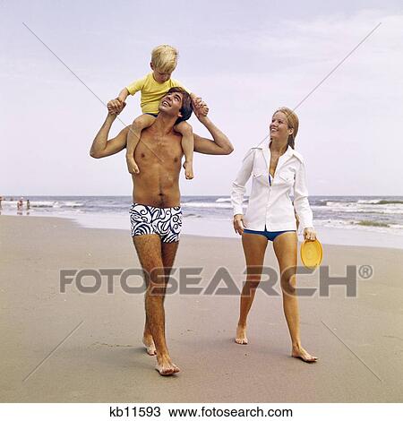 1970s YOUNG FAMILY WALKING DOWN BEACH TODDLER RIDING ON FATHERS SHOULDERS View Large Photo Image Stock Image - 1970s YOUNG FAMILY WALKING DOWN BEACH TODDLER RIDING ON FATHERS SHOULDERS. Fotosearch