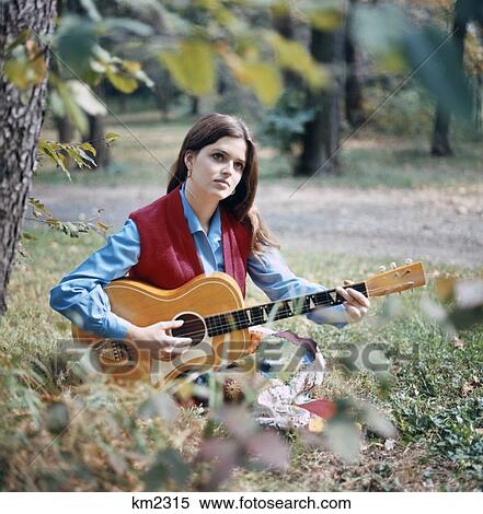 Stock Photography - 1970S Young Woman Outdoors Playing Guitar. Fotosearch