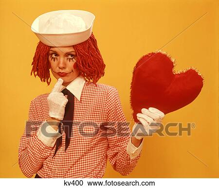 1970s YOUNG WOMAN RAGGEDY ANN WIG COSTUME SAILOR HAT YELLOW BACKGROUND HOLDING UP HEART View Large Photo Image Stock Image - 1970s YOUNG WOMAN RAGGEDY ANN WIG COSTUME SAILOR HAT YELLOW BACKGROUND HOLDING UP HEART. Fotosearch