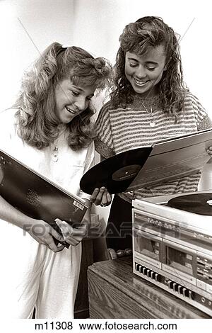 1980s 2 TEENAGE GIRLS READING VINYL RECORD ALBUM JACKET COVERS LISTENING TO LONG PLAYING PHONOGRAPH PLAYER View Large Photo Image Stock Photo - 1980s 2 TEENAGE GIRLS READING VINYL RECORD ALBUM JACKET COVERS LISTENING TO LONG PLAYING PHONOGRAPH PLAYER. Fotosearch