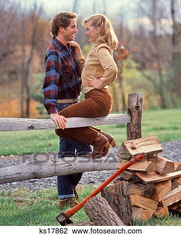 1980s ROMANTIC COUPLE SITTING SPLIT RAIL FENCE BY WOOD PILE WEARING AUTUMN SEASON CLOTHES View Large Photo Image Stock Image - 1980s ROMANTIC COUPLE SITTING SPLIT RAIL FENCE BY WOOD PILE WEARING AUTUMN SEASON CLOTHES. Fotosearch