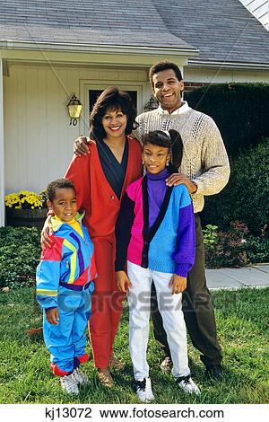 Stock Image - 1990s AFRICAN AMERICAN FAMILY ON FRONT LAWN. Fotosearch