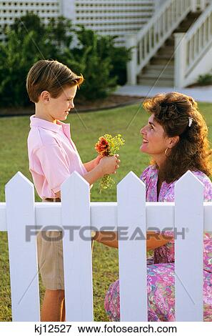 1990s BOY GIVING FLOWERS TO HIS MOTHER View Large Photo Image Stock Photo - 1990s BOY GIVING FLOWERS TO HIS MOTHER. Fotosearch