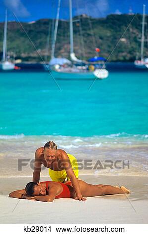 1990s MAN LEANING OVER WOMAN SUNBATHING ON BEACH CARRIACOU WEST INDIES View Large Photo Image Picture - 1990s MAN LEANING OVER WOMAN SUNBATHING ON BEACH CARRIACOU WEST INDIES. Fotosearch