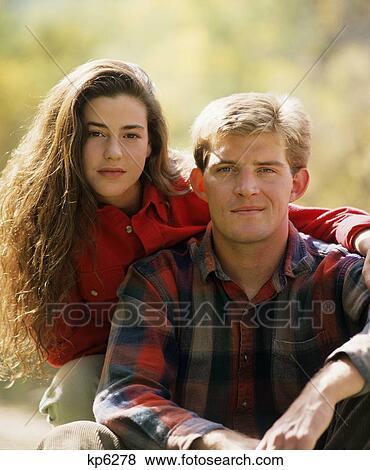 Stock Photo - 1990s PORTRAIT OF SERIOUS YOUNG COUPLE LOOKING AT CAMERA OUTDOORS IN AUTUMN. Fotosearch
