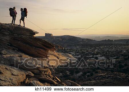 Stock Photo - 2 ANONYMOUS SILHOUETTED HIKERS ON THE WAY TO CANYONLANDS NEAR MOAB UTAH USA. Fotosearch