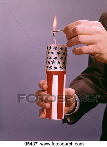 MALE HANDS LIGHTING A GIANT RED WHITE AND BLUE AMERICAN FIRECRACKER View Large Photo Image Stock Photo - MALE HANDS LIGHTING A GIANT RED WHITE AND BLUE AMERICAN FIRECRACKER. Fotosearch