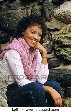 Picture - PORTRAIT OF YOUNG AFRICAN AMERICAN WOMAN LOOKING AT CAMERA SMILING WEARING PINK SWEATER OVER SHOULDERS. Fotosearch