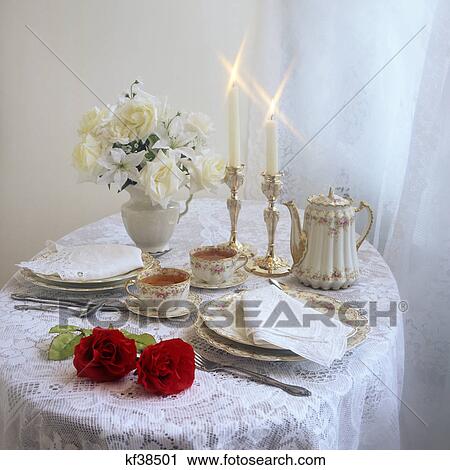 Stock Image - TABLE SET FOR TEA SERVICE FOR 2 WITH CANDLES AND BOUQUET OF FLOWERS. Fotosearch