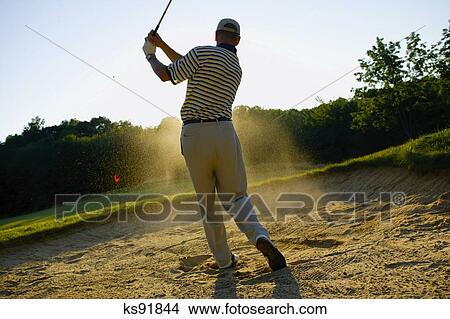 man-hitting-golf-ball-out-of-sand-pit-picture__ks91844.jpg