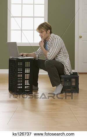 Man Sitting On Milk Crate With Laptop Computer Stock Photo