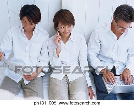 A woman and two men sitting on a bench and working View Large Photo Image Stock Photography - A woman and two men sitting on a bench and working. Fotosearch