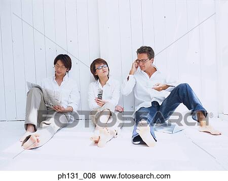 Stock Photo - A woman and two men sitting on the floor and working. Fotosearch