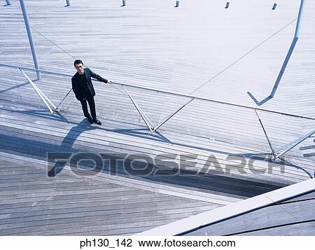 Aerial view of a man standing on a bridge View Large Photo Image Stock Image - Aerial view of a man standing on a bridge. Fotosearch