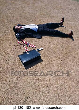 Stock Image - Asian Businessman lying flat on the ground. Fotosearch