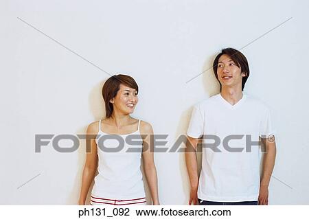 Stock Image - Asian couple leaning against the wall. Fotosearch