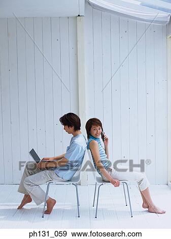 Asian couple sitting with their backs to each other View Large Photo Image Stock Photo - Asian couple sitting with their backs to each other. Fotosearch