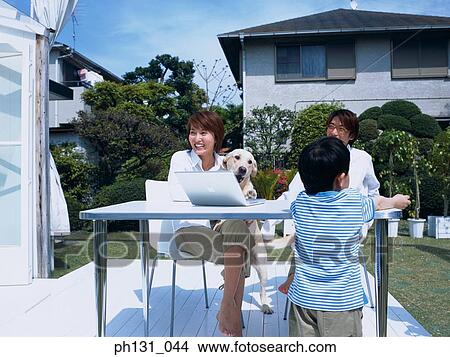 Asian family sitting out with their pet View Large Photo Image Picture - Asian family sitting out with their pet. Fotosearch