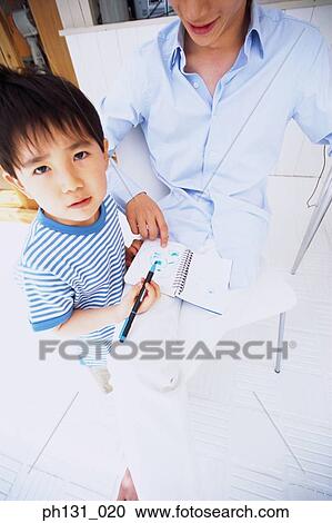 Stock Image - Asian father and son coloring in a notebook. Fotosearch