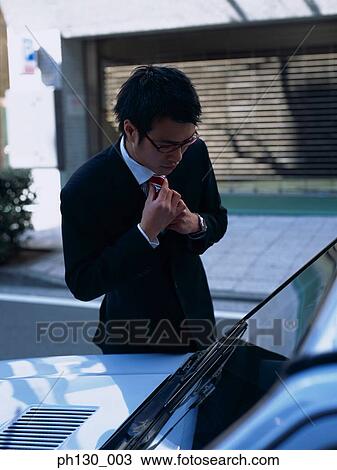 Asian Man fixing his tie in the windscreen reflection View Large Photo Image Stock Image - Asian Man fixing his tie in the windscreen reflection. Fotosearch