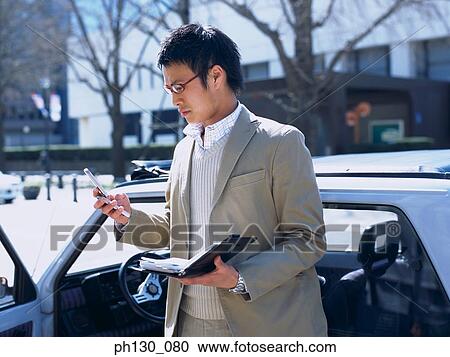 Stock Image - Asian Man looking at his cell phone. Fotosearch