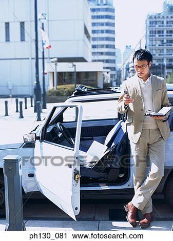 Stock Image - Asian Man looking at his cell phone. Fotosearch