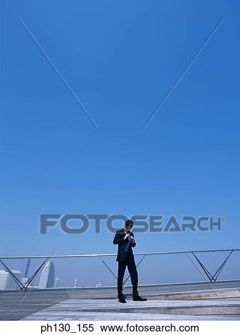 Asian Man on a bridge fixing his tie View Large Photo Image Stock Photography - Asian Man on a bridge fixing his tie. Fotosearch