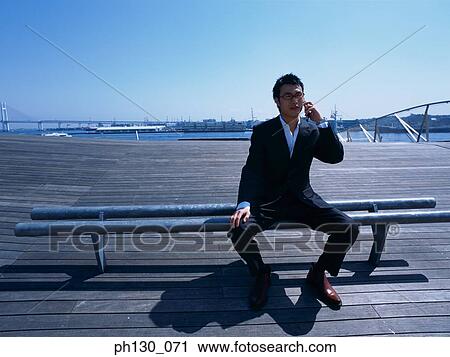 Asian Man on a pier talking on his cell phone View Large Photo Image Stock Image - Asian Man on a pier talking on his cell phone. Fotosearch