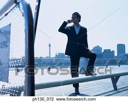 Asian Man on a pier talking on his cell phone View Large Photo Image Stock Image - Asian Man on a pier talking on his cell phone. Fotosearch