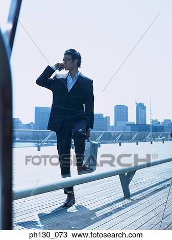 Asian Man on a pier talking on his cell phone View Large Photo Image Stock Image - Asian Man on a pier talking on his cell phone. Fotosearch