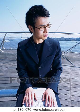 Asian Man on a pier working on his laptop View Large Photo Image Stock Image - Asian Man on a pier working on his laptop. Fotosearch