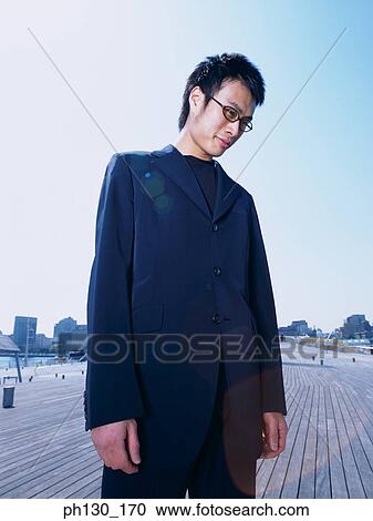 Stock Image - Asian Man on a walkway looking down. Fotosearch