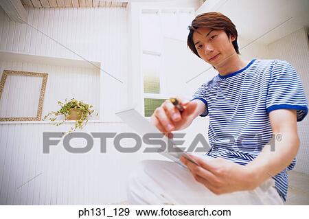 Stock Photo - Asian man pointing a pen at the camera. Fotosearch