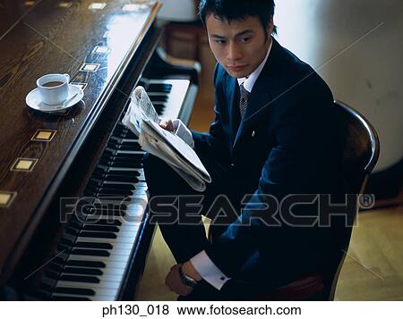Stock Photo - Asian Man sitting by a piano. Fotosearch