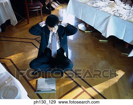 Stock Photo - Asian Man sitting on the floor with a laptop. Fotosearch