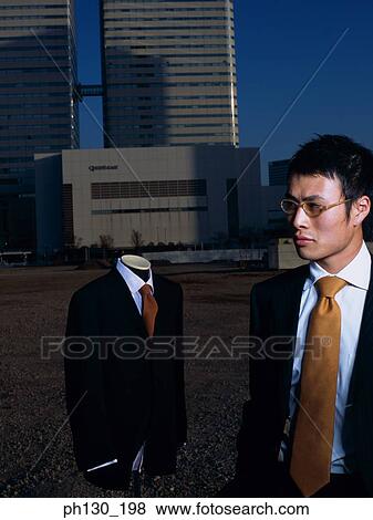 Asian Man standing in a lot with a mannequin View Large Photo Image Stock Photo - Asian Man standing in a lot with a mannequin. Fotosearch