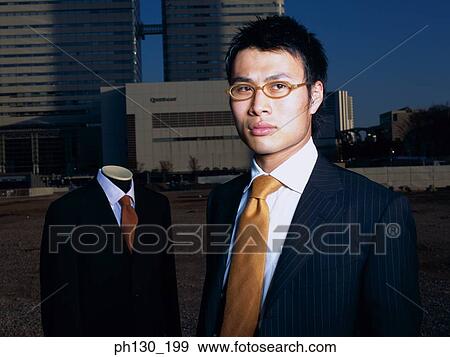 Asian Man standing in a lot with a mannequin View Large Photo Image Stock Photo - Asian Man standing in a lot with a mannequin. Fotosearch