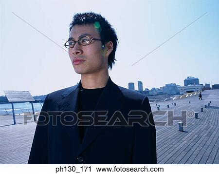 Asian man standing on a walkway View Large Photo Image Stock Image - Asian man standing on a walkway. Fotosearch