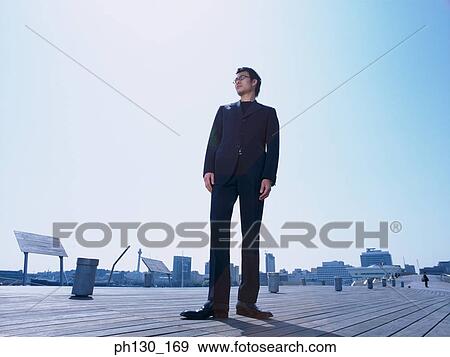 Asian man standing on a walkway View Large Photo Image Stock Photo - Asian man standing on a walkway. Fotosearch