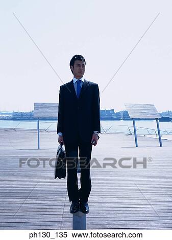 Asian man standing on a walkway View Large Photo Image Stock Photography - Asian man standing on a walkway. Fotosearch