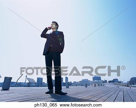 Asian Man talking on a cell phone View Large Photo Image Stock Photography - Asian Man talking on a cell phone. Fotosearch
