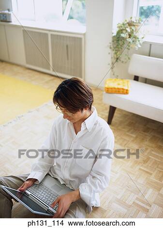 Picture - Asian man using a laptop. Fotosearch