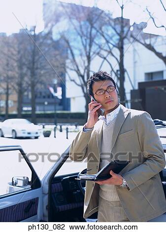 Asian Man using his cell phone View Large Photo Image Stock Image - Asian Man using his cell phone. Fotosearch