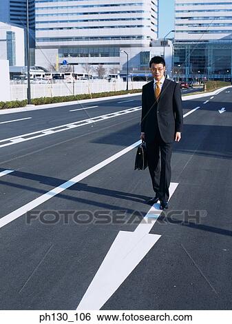 Asian Man walking in the middle of the street View Large Photo Image Stock Photograph - Asian Man walking in the middle of the street. Fotosearch