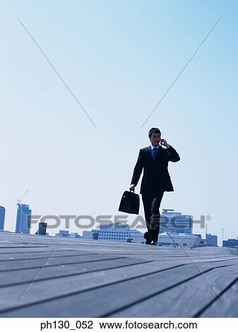 Asian Man walking on a walkway View Large Photo Image Stock Image - Asian Man walking on a walkway. Fotosearch
