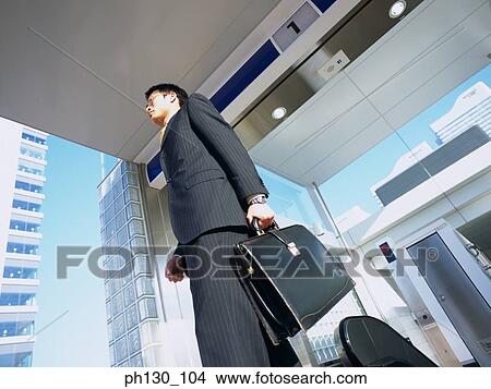 Asian Man walking out of an office View Large Photo Image Picture - Asian Man walking out of an office. Fotosearch