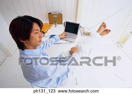 Asian man working on a desk View Large Photo Image Stock Image - Asian man working on a desk. Fotosearch