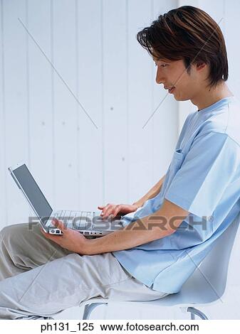 Asian man working on a laptop View Large Photo Image Stock Photography - Asian man working on a laptop. Fotosearch